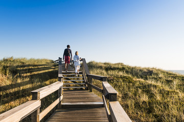 People on wooden footpath on dune on the  beach in Germany.