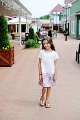 Stylish brunette kid girl walking on the shopping city street