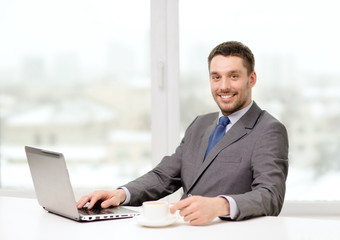 smiling businessman with laptop and coffee