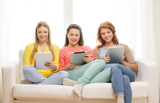 three smiling teenage girls with tablet pc at home