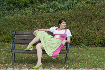 Junge Frau in Trachtenkleid auf der Gartenbank