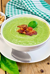 Soup puree with bacon and spoon on board