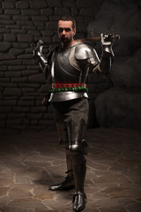 Medieval Knight posing with sword in a dark stone background