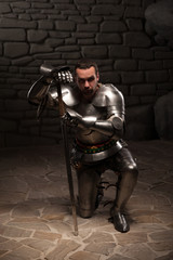 Fototapeta na wymiar Medieval knight kneeling with sword