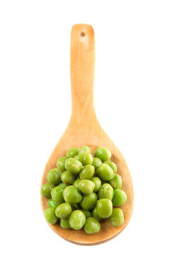 Green peas on wooden spoon over white background