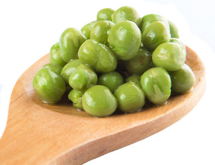 Green peas on wooden spoon over white background