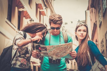Multi ethnic friends tourists with map in old city