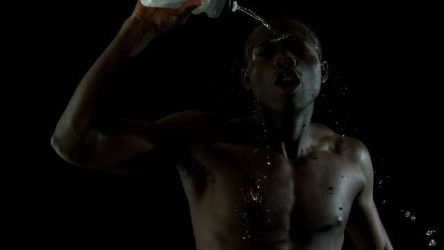 Shirtless man jogging and pouring water over himself