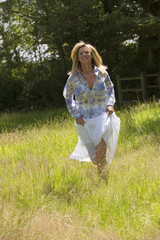 Attractive woman in summer outfit running through a field