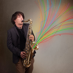 Fototapeta na wymiar Attractive musician playing on saxophone while colorful abstract