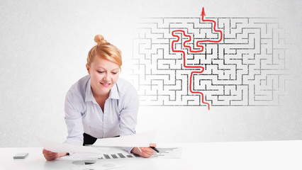 Business woman at desk with labyrinth and arrow