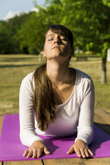 Pretty woman doing yoga exercises in the park.