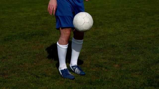 Football player in blue controlling the ball on pitch