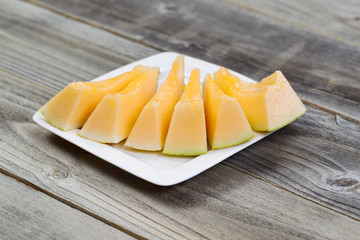 Fresh Melon Slices on White Plate with rustic wood underneath