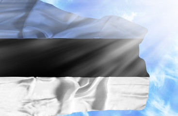 Estonia waving flag against blue sky with sunrays