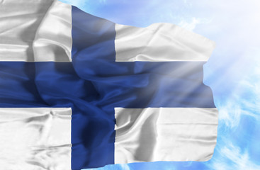 Finland waving flag against blue sky with sunrays