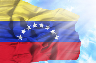 Venezuela waving flag against blue sky with sunrays