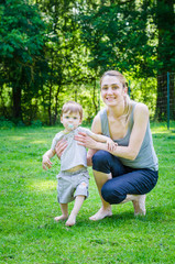 Fototapeta premium Little cute baby boy walking with young mother in park