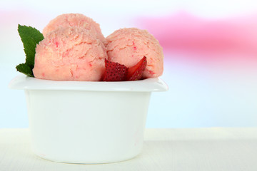 Tasty ice cream scoops in bowl, on wooden table