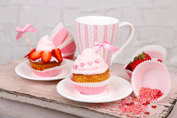 Tasty cup cakes with cream on wooden table