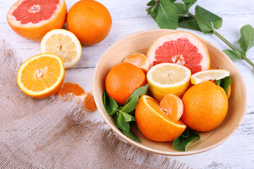 Fresh citrus fruits with green leaves in bowl