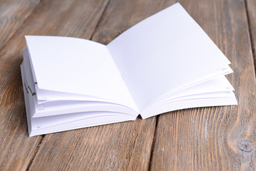 Open white book on wooden table, close-up