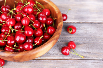 Ripe sweet cherries in bowl on wooden table