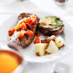 steak covered in tomatoes with potatoes