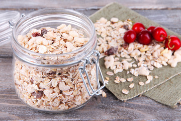Homemade granola in glass jar, on color wooden background
