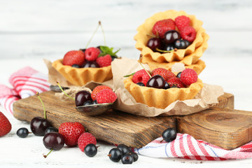 Tasty tartlets with berries on wooden table