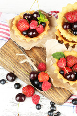 Tasty tartlets with berries on wooden table