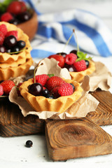 Tasty tartlets with berries on wooden table