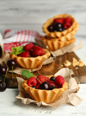 Tasty tartlets with berries on wooden table