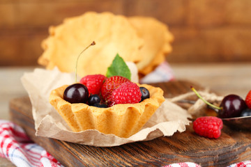 Tasty tartlets with berries on wooden table