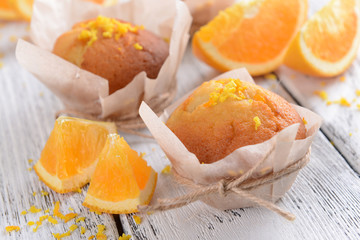 Tasty cupcakes with orange on table close-up
