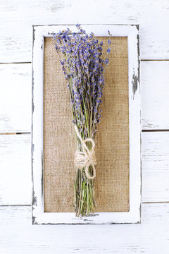 Lavender flowers and wooden frame on wooden background