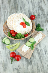 Tasty crispbreads with vegetables on wooden background