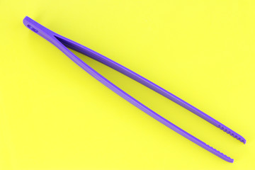 Plastic kitchen tongs on yellow background