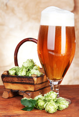 Glass of beer and hops, on wooden table