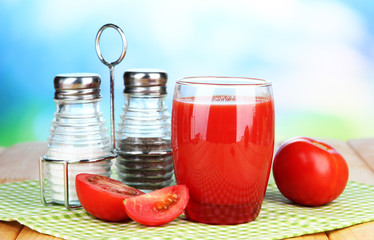 Tomato juice in glass, on wooden  table, on bright background