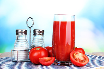 Tomato juice in glass, on wooden  table, on bright background
