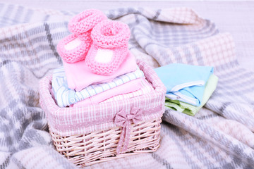 Obraz na płótnie Canvas Baby clothes in basket on plaid in room