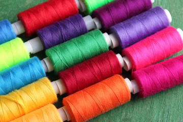 Multicolor sewing threads on wooden background
