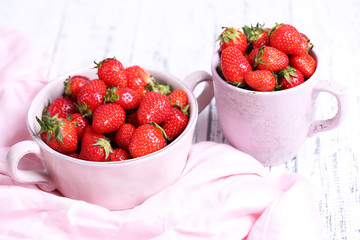 Ripe sweet strawberries in pot and mug