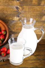 Obraz na płótnie Canvas Ripe sweet strawberries in wooden bowl and jug with milk