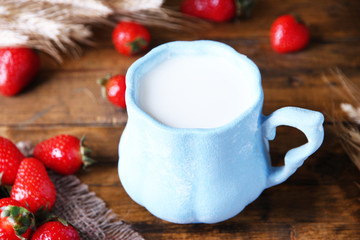 Ripe sweet strawberries and mug with milk