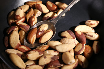 Tasty brasil nuts in pan on wooden background