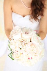 Bride holding wedding bouquet of white peonies, close-up,