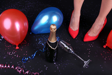 Legs with confetti, champagne and balloons on the floor