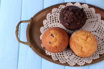 Tasty muffins on tray, on color wooden background